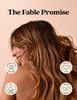 A woman with long, wavy brown hair is shown in profile against a soft peach background, with the text 'The Fable Promise' at the top and four circular icons highlighting product benefits: suitable for all hair types, cruelty free, no silicone, and vegan formula.